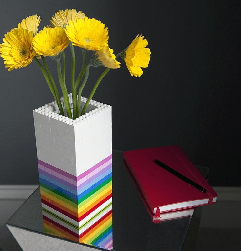 LEGO built vase displaying yellow flowers beside a notebook